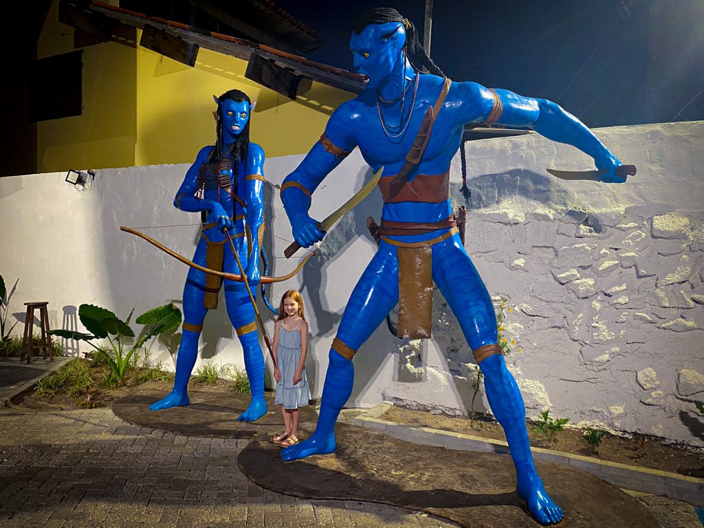 a child in front of two large avatar statues