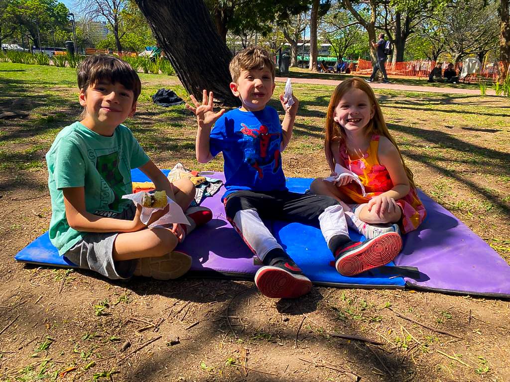 three children on a blanket in a park