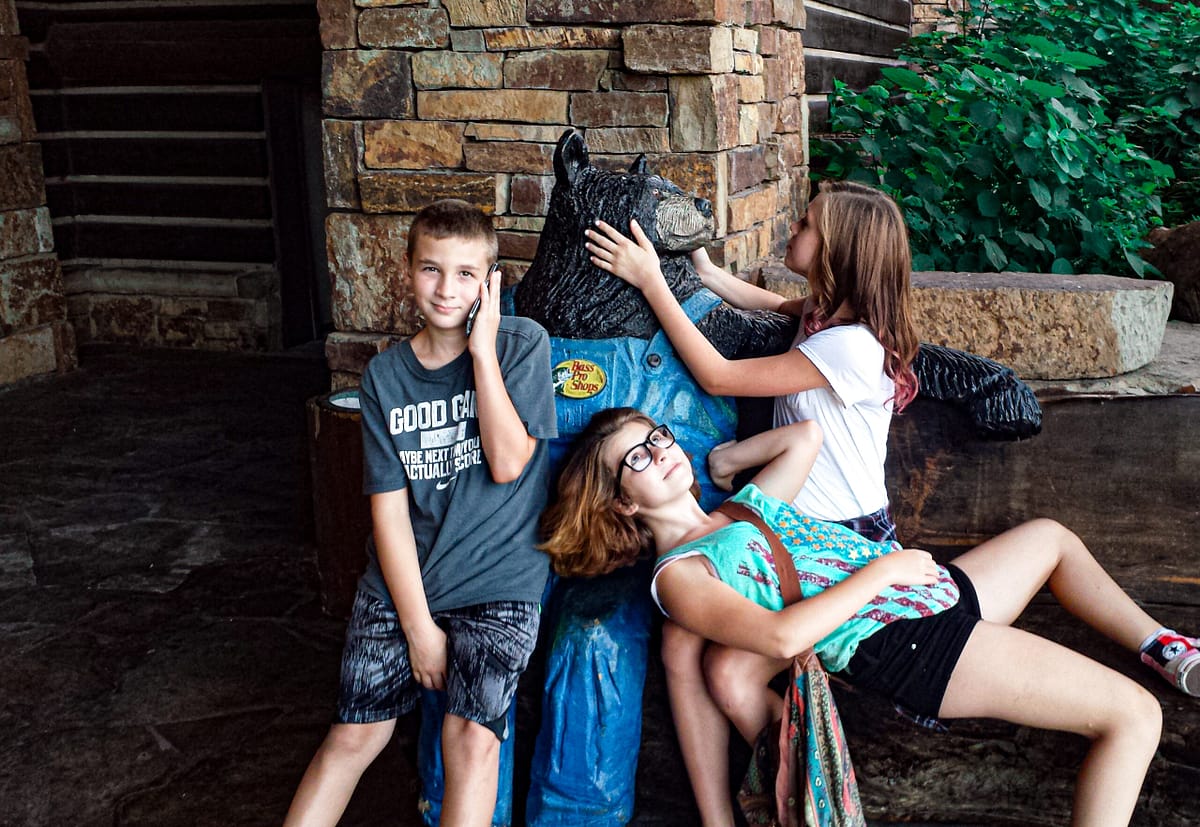 3 kids sitting on a fake bear