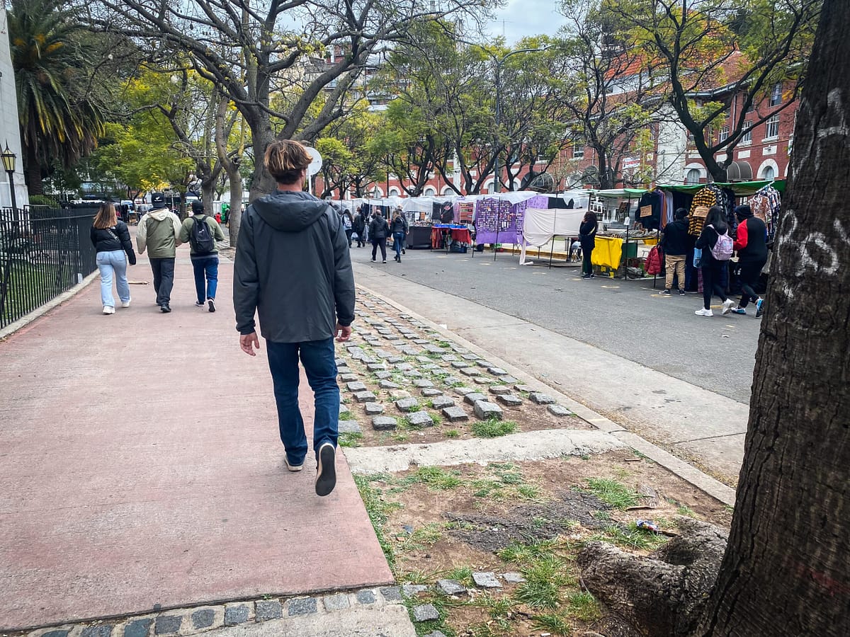 man walking past street market