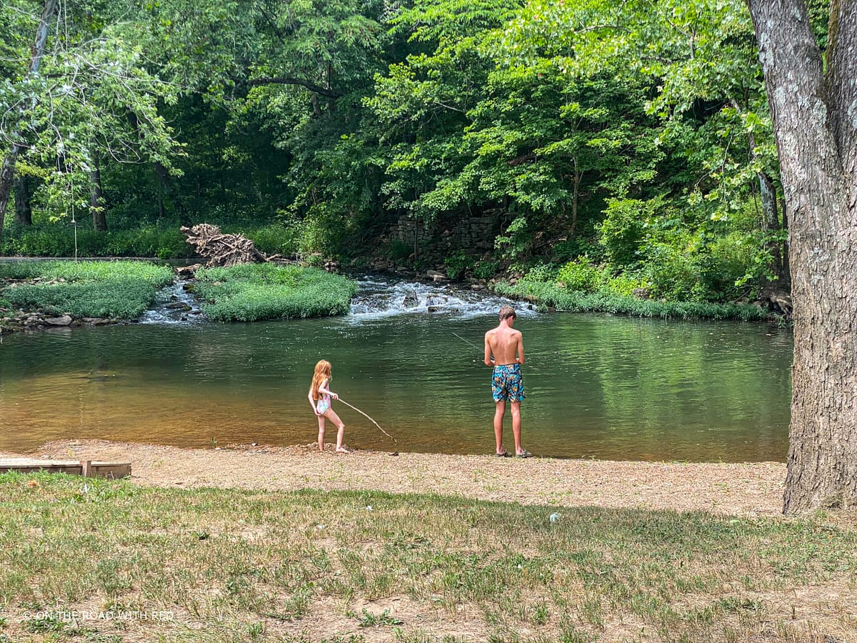 a boy and girl in front of a creek