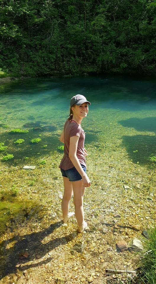 a girl standing in front of a spring