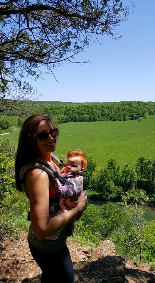 a woman holding a baby overlooking a valley
