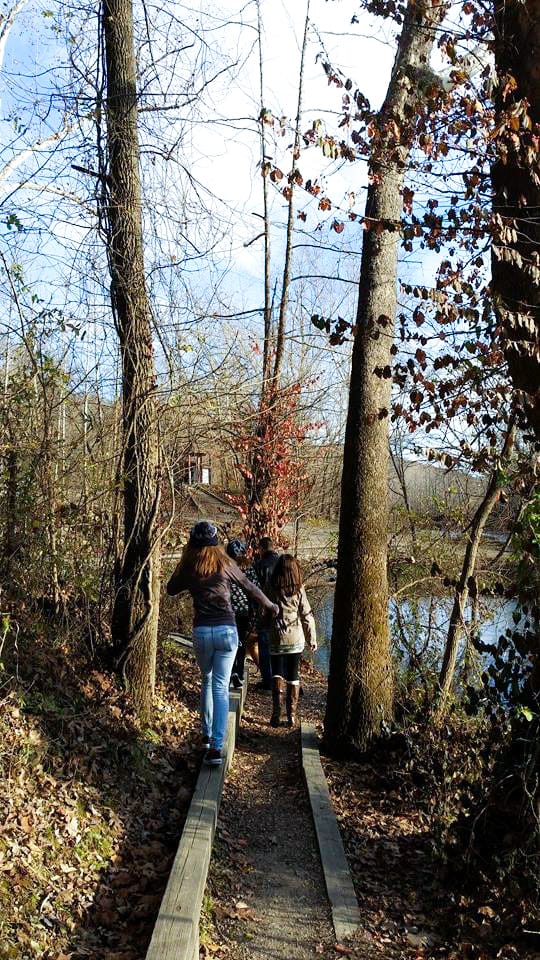 a woman and teenager walking on a wooded path.