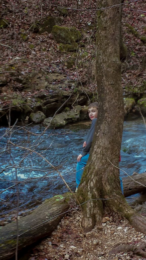 a boy leaning against a tree