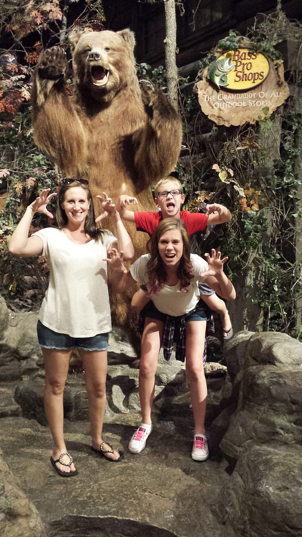 a women, teenager, and child in front of a stuffed bear