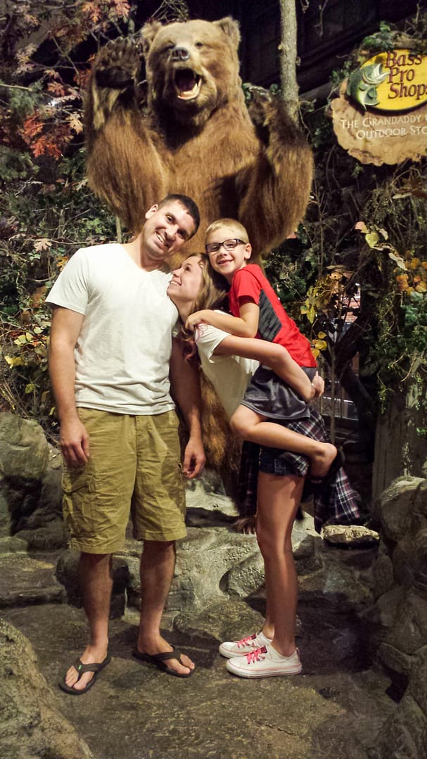 a man and a teenager and a child in front of a stuffed bear