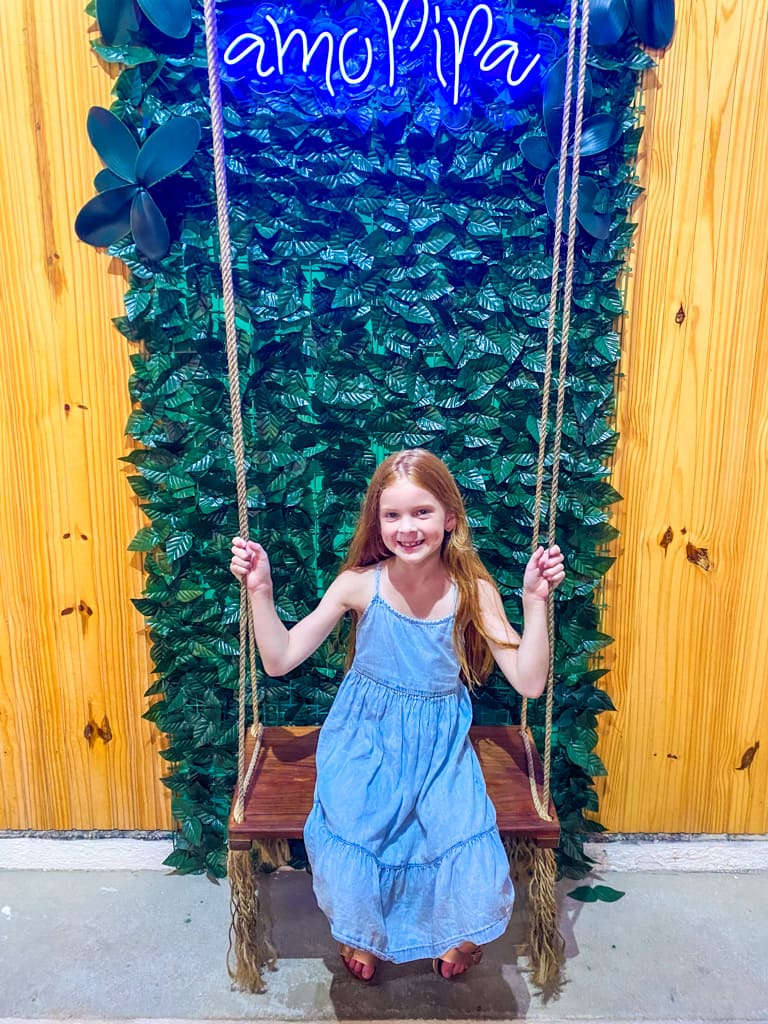 a child in a wooden swing in front of Ivy