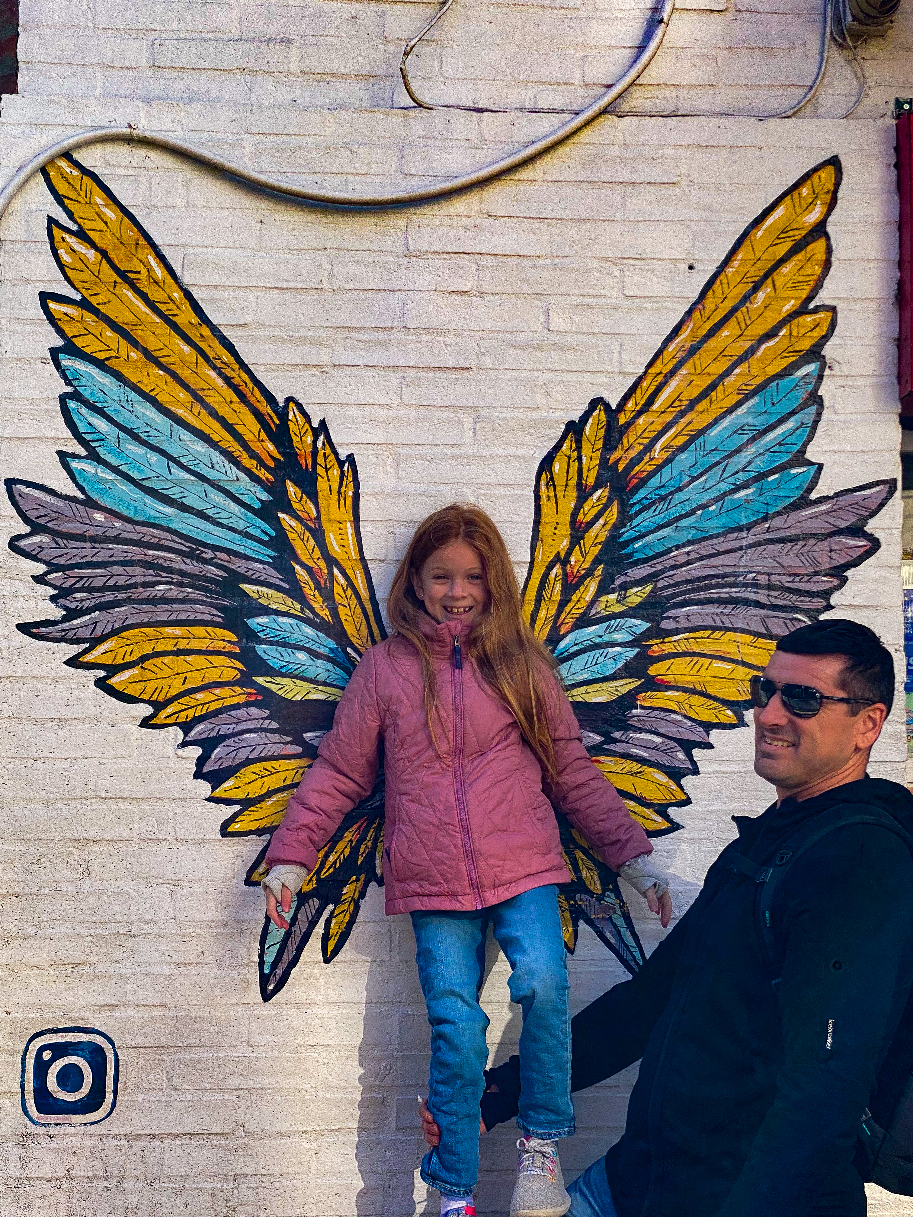 a child in front of angel wings being held by her dad