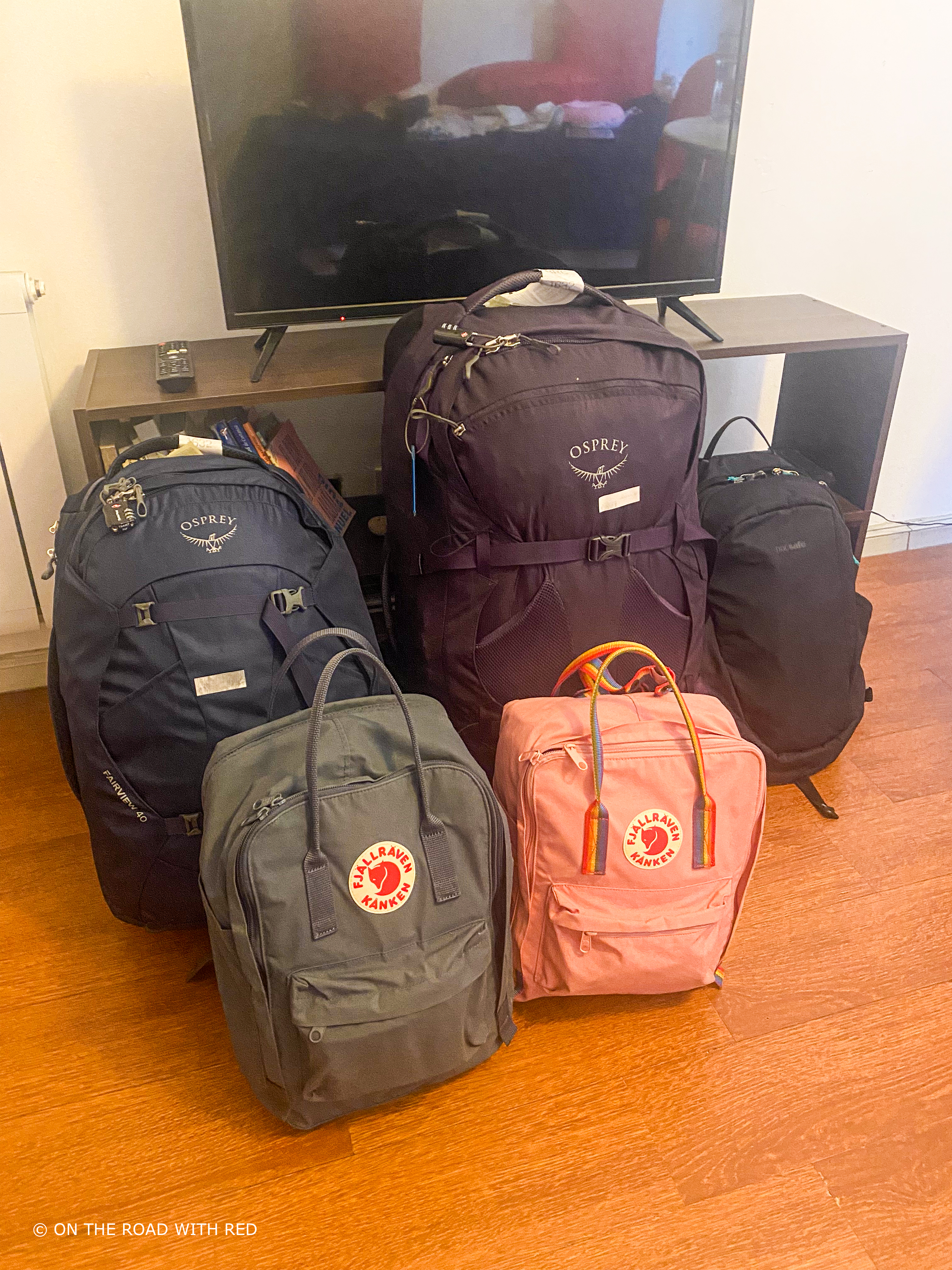 5 full backpacks sitting on a floor