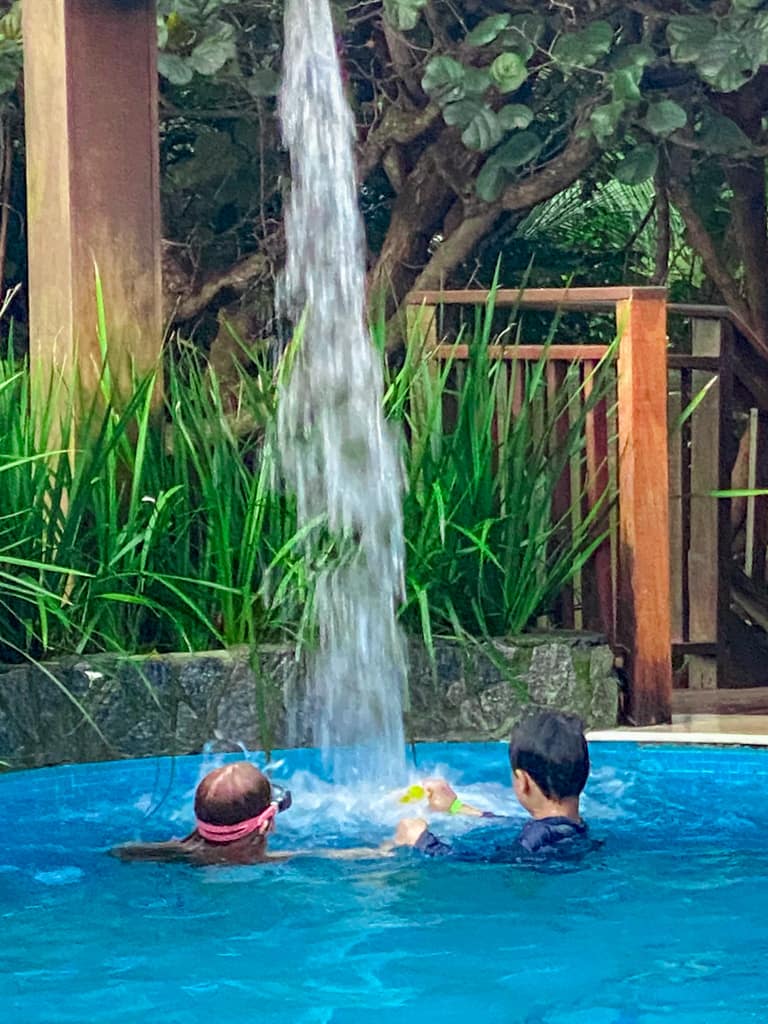2 children playing in a pool waterfall