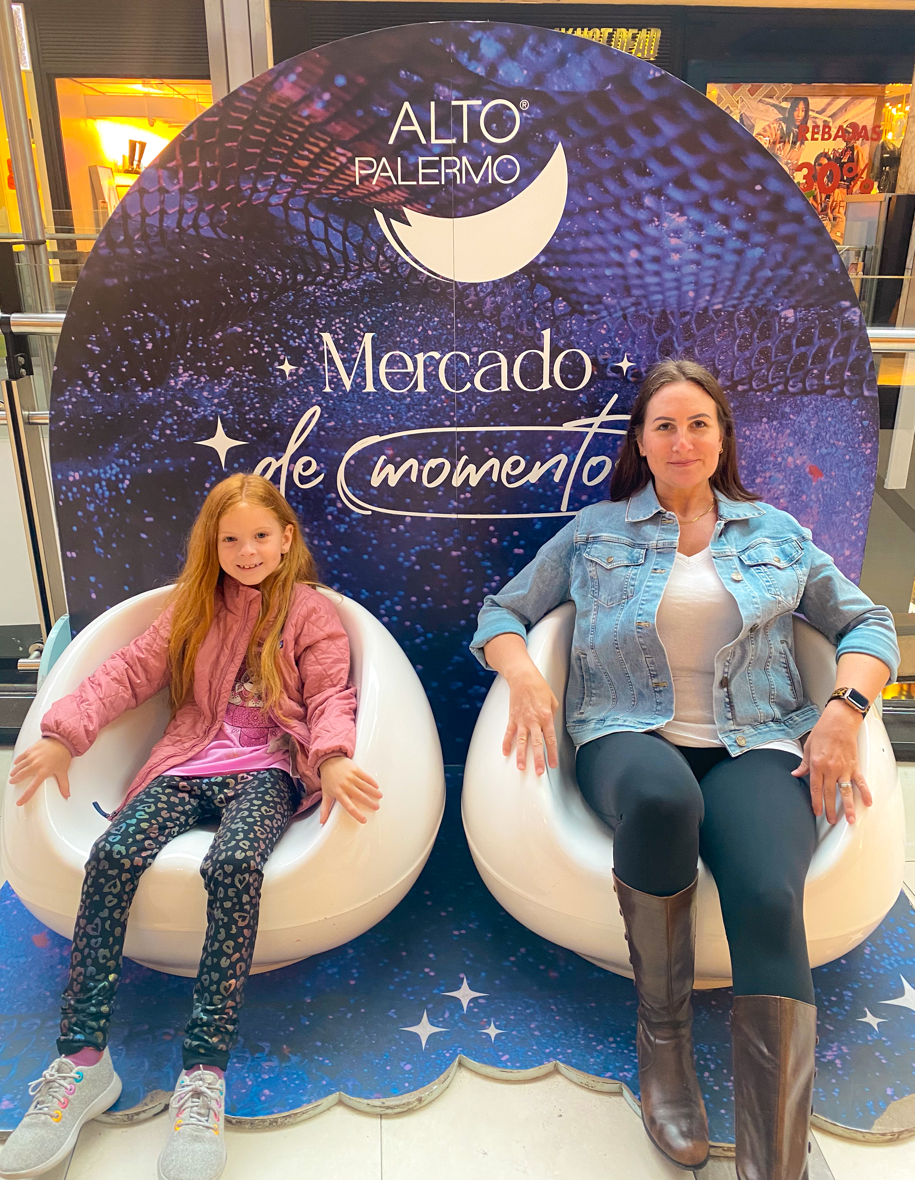 a woman and a girl sitting in chairs in a shopping mall