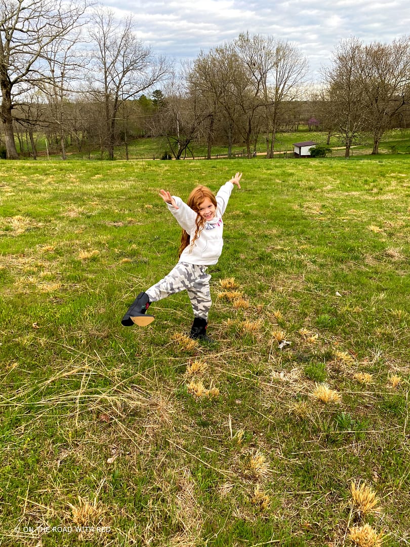 a redhead child standing excitedly in a field in the country