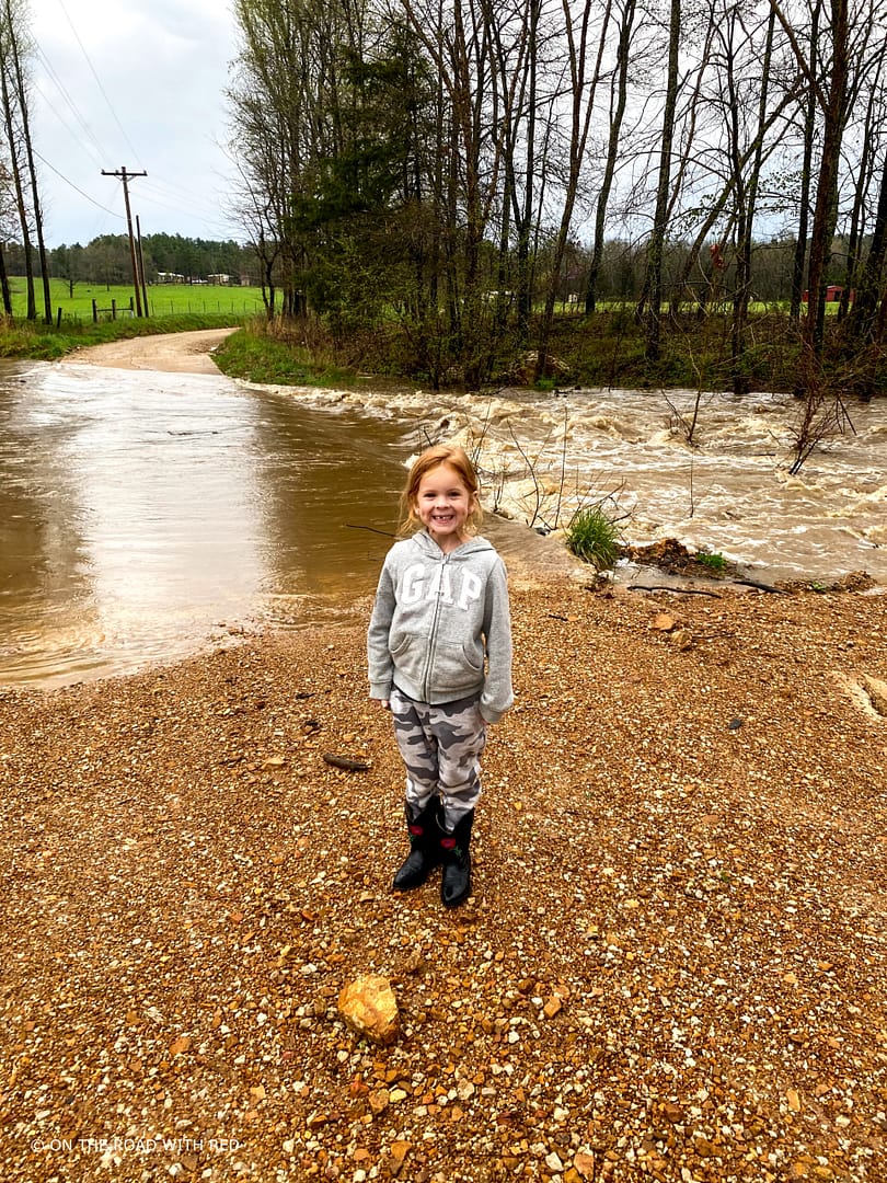 a child in front of a flooded creek.