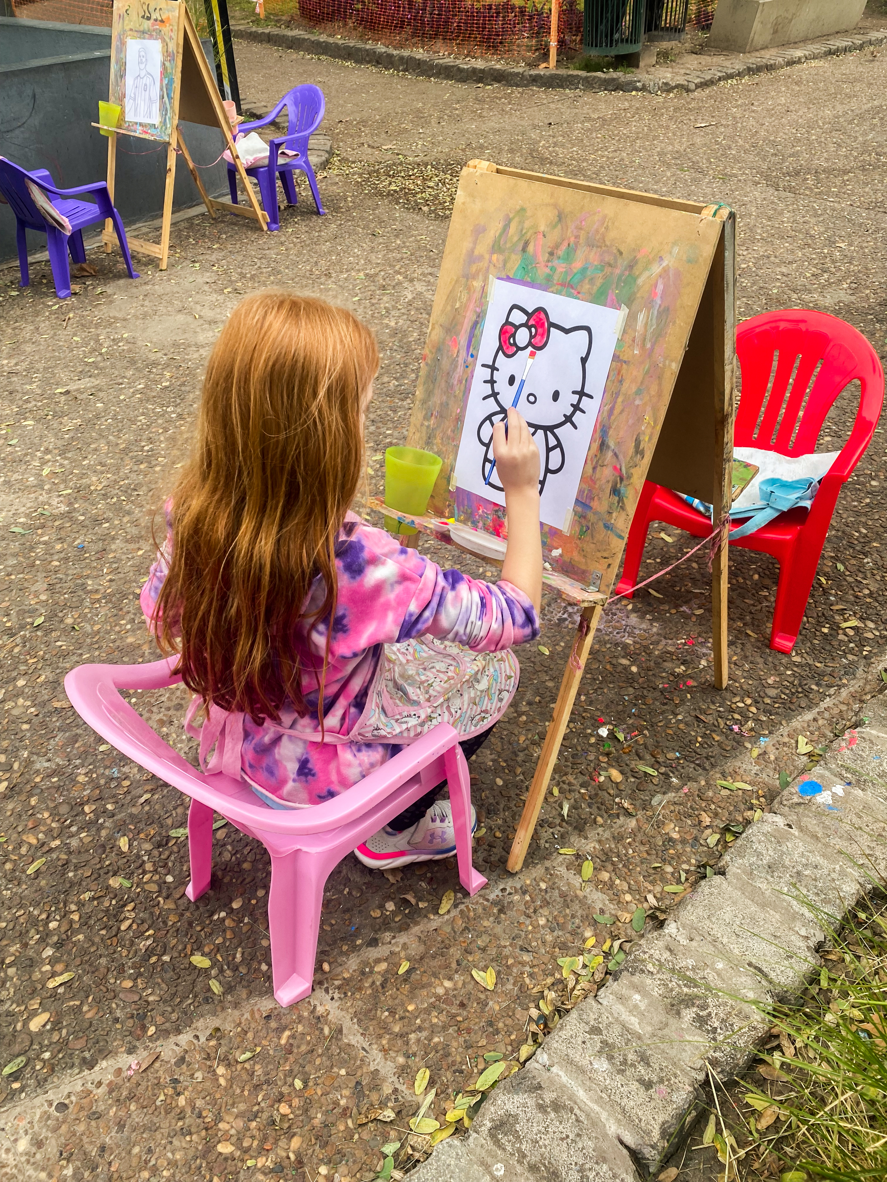 Kaia painting a picture outside on an art easel in a park in Buenos Aires.