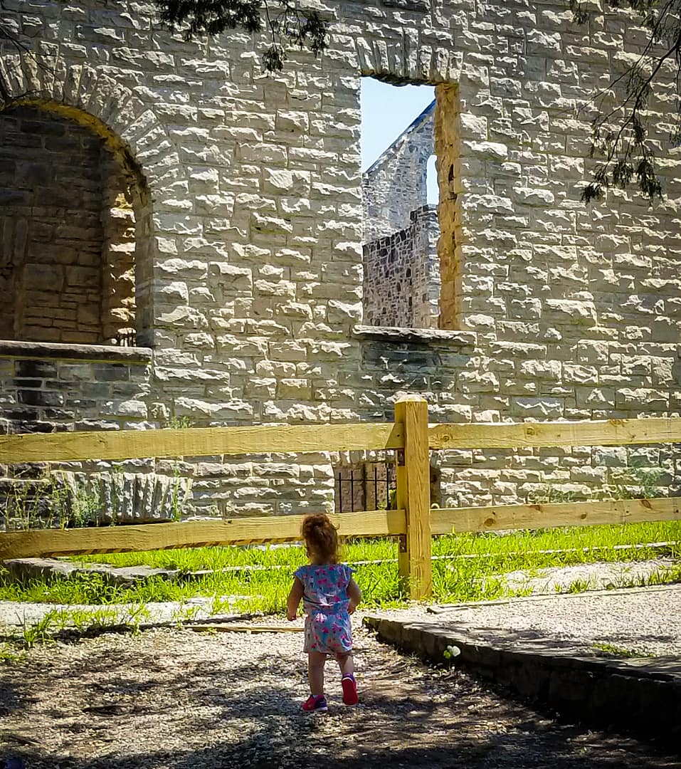 a toddler standing in front of historic ruins