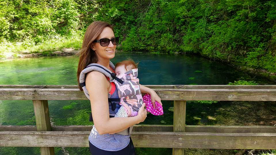 a woman holding a baby in front of a spring